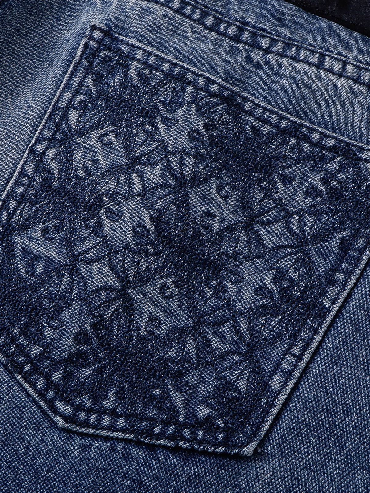 Tonal gothic pattern on the back pocket of the blue washed jeans