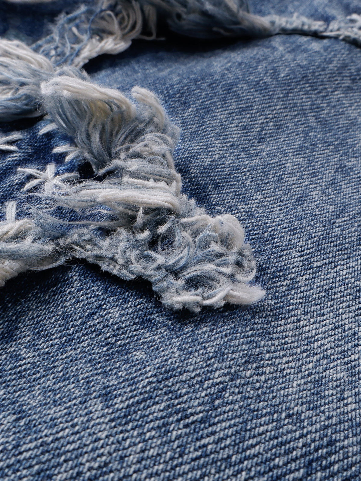 Close-up of frayed distressing and the washed blue denim texture