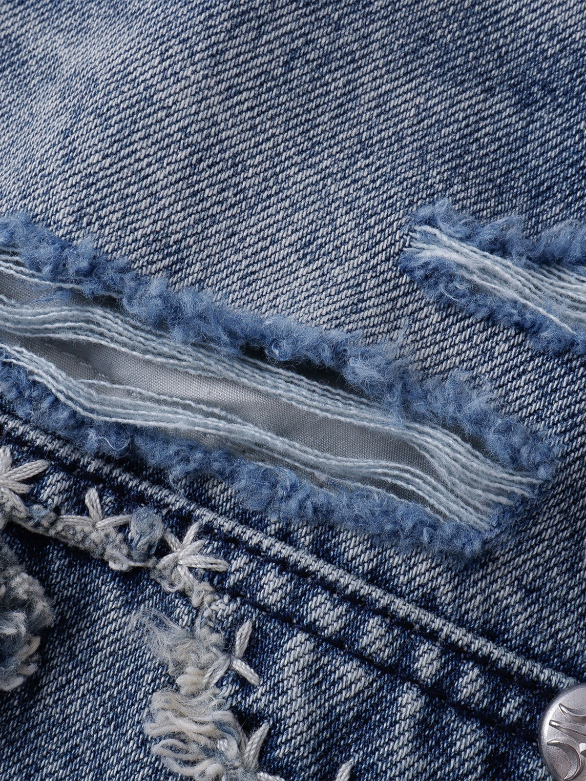 Raw-edged distressed denim panel with layered fraying and cross-stitch details