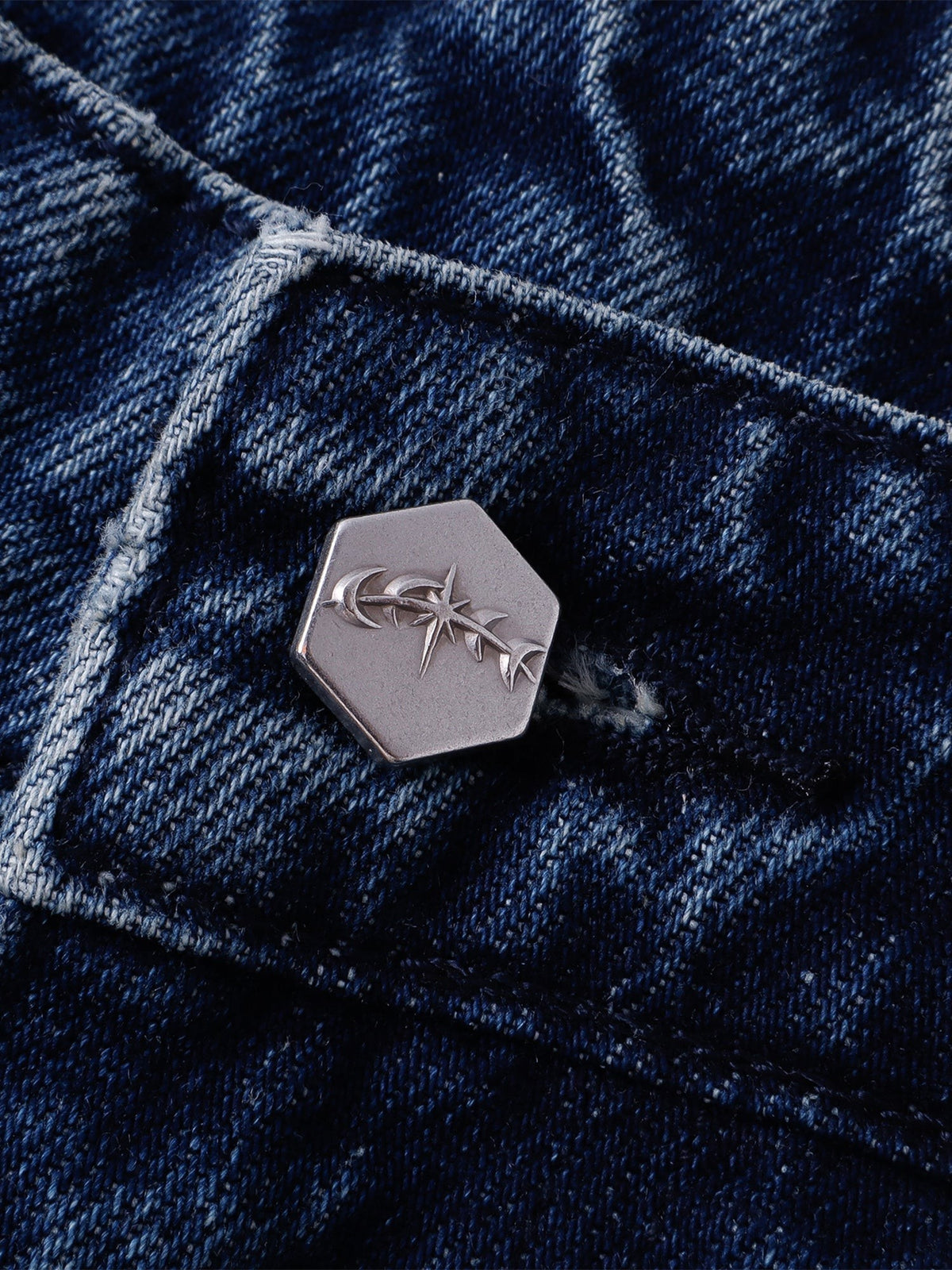 Close-up of the hexagonal astral logo button on washed blue denim
