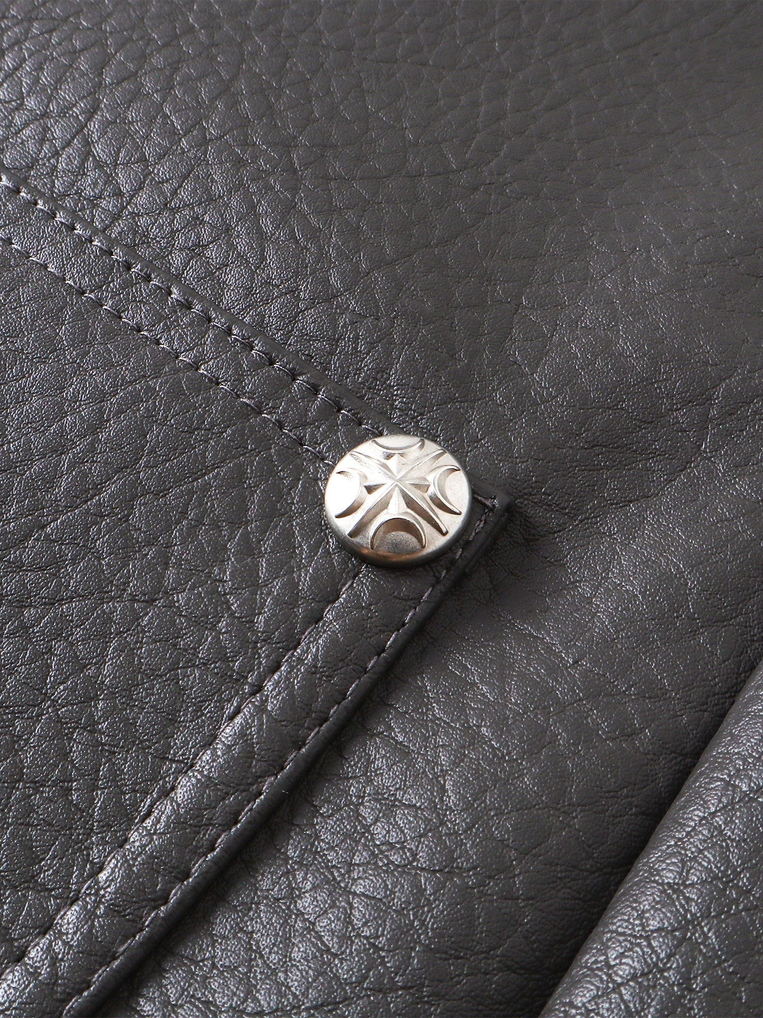 Close-up of the metal button on TBHNP faux-leather shorts — men's streetwear detail