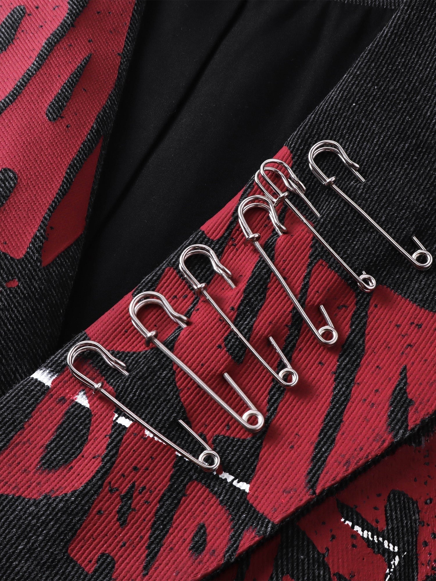 Close-up of the red graphic and safety-pin hardware on TBHNP spray-painted blazer — men's streetwear detail