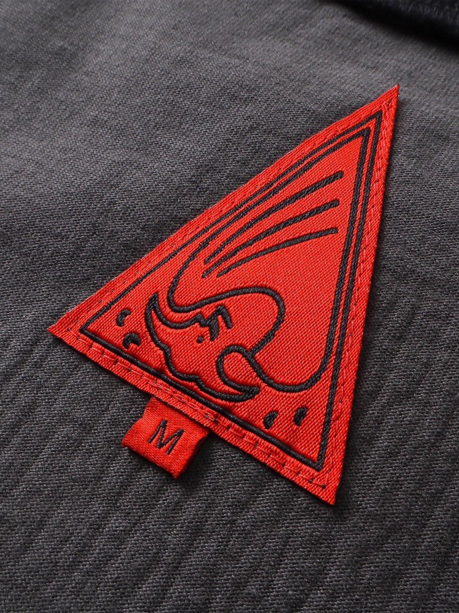 Close-up of the red triangle logo patch on TBHNP black knight tee — men's streetwear detail
