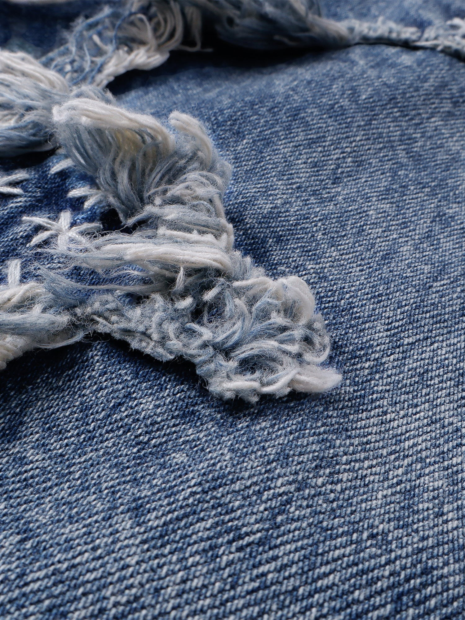 Detalle del deshilachado y la textura del denim azul lavado
