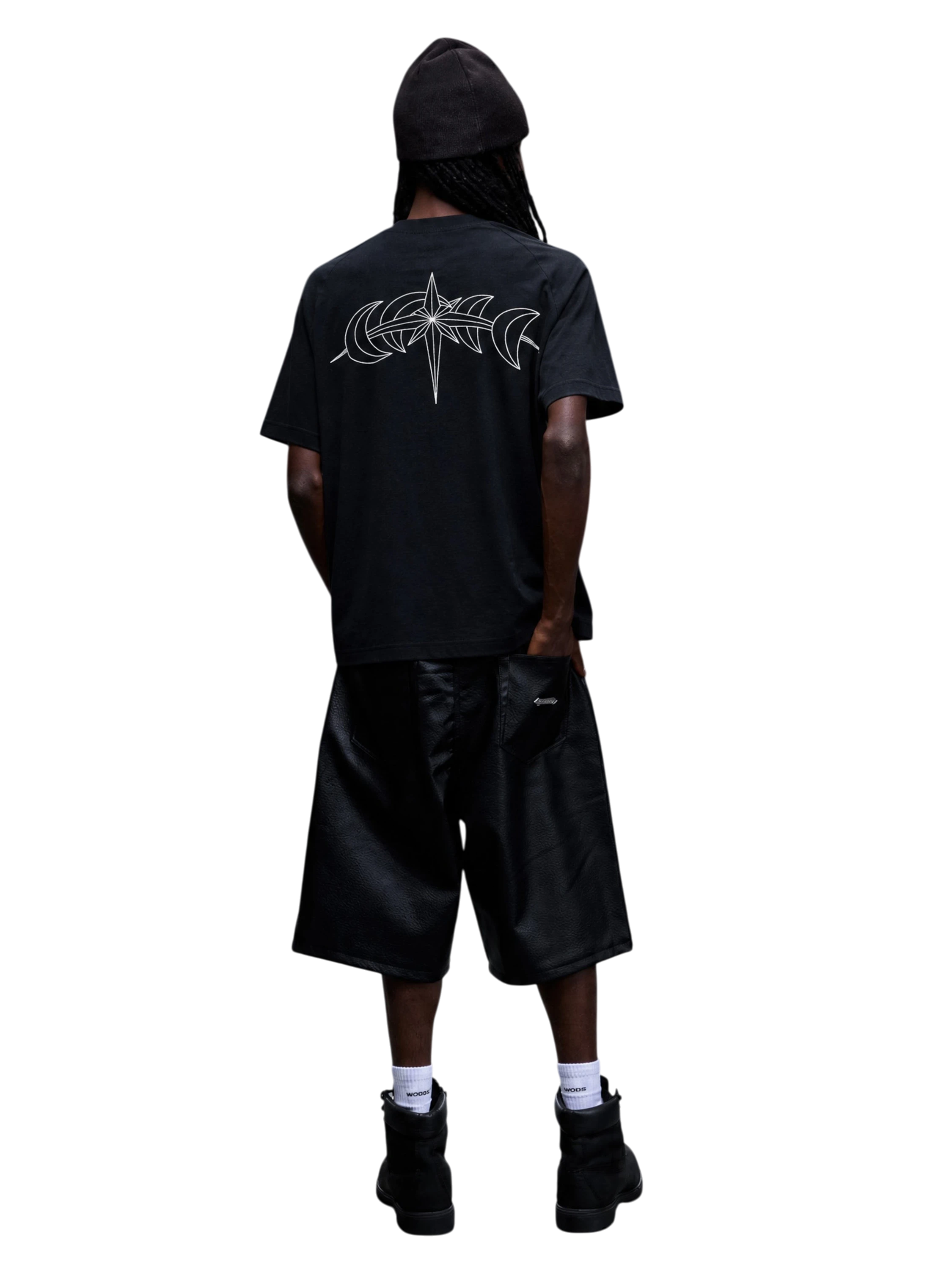 Modelo con camiseta negra Luminous Dawn y gráfica trasera de estrella astral y medias lunas