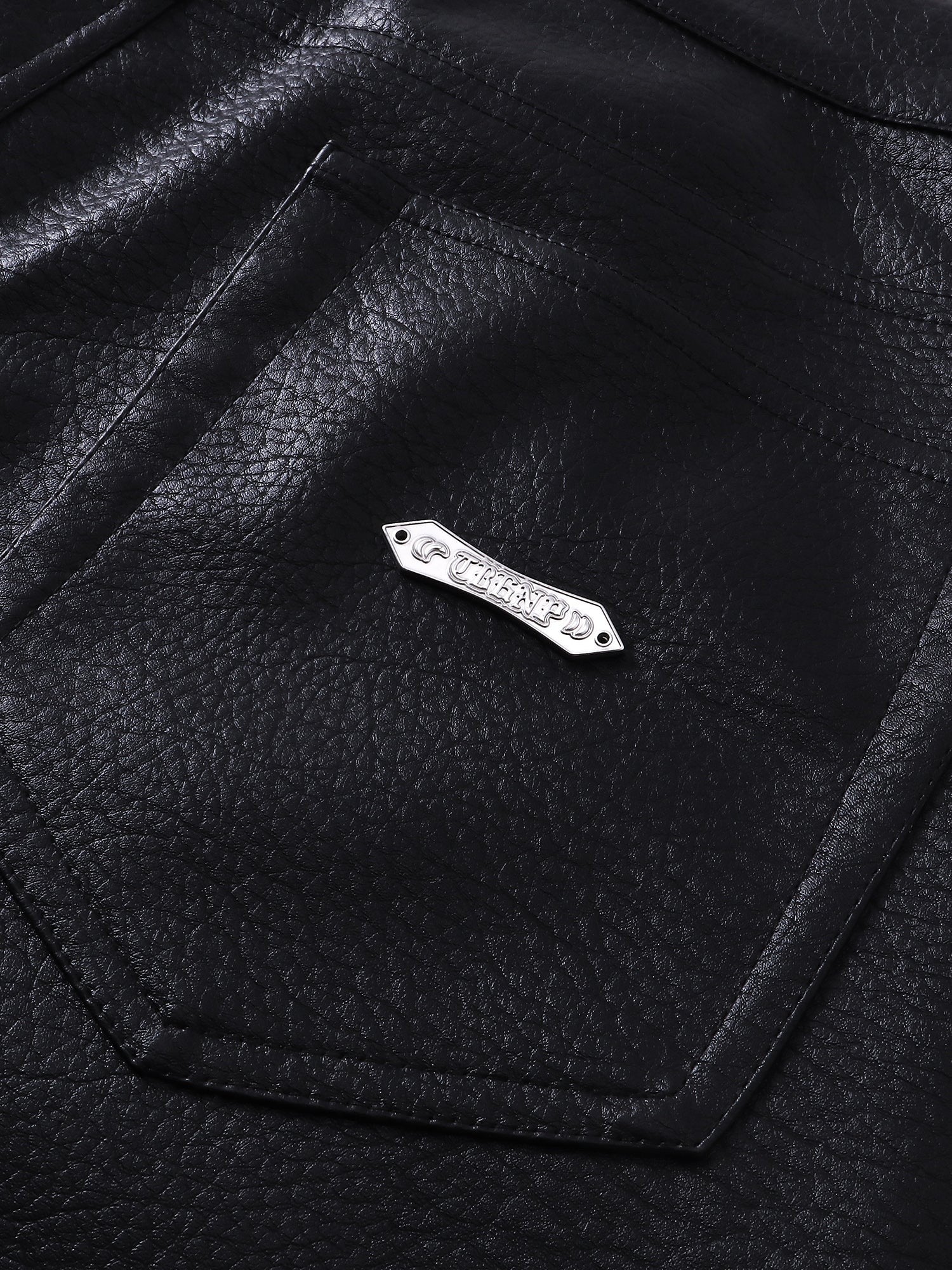 Close-up of the metal label on TBHNP black faux-leather shorts — men's streetwear detail