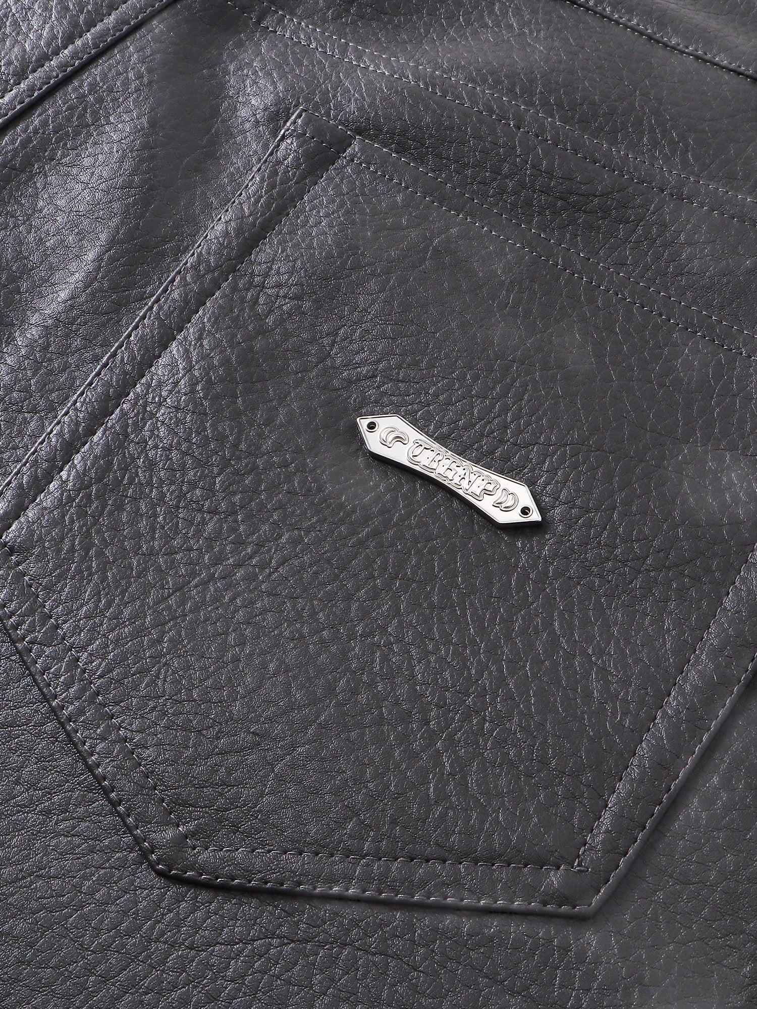 Close-up of the pocket and metal label on TBHNP faux-leather shorts — men's streetwear detail