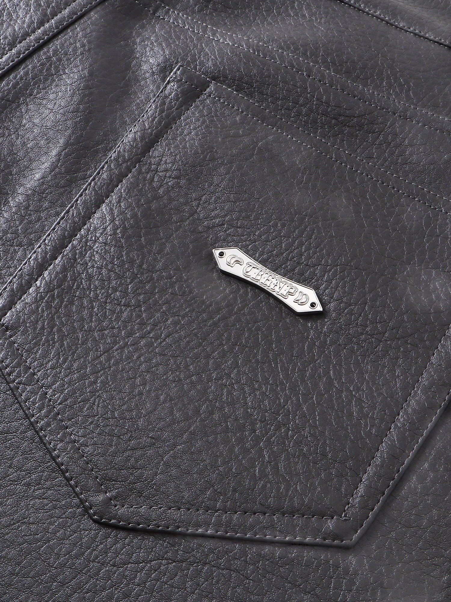Close-up of the pocket and metal label on TBHNP faux-leather shorts — men's streetwear detail