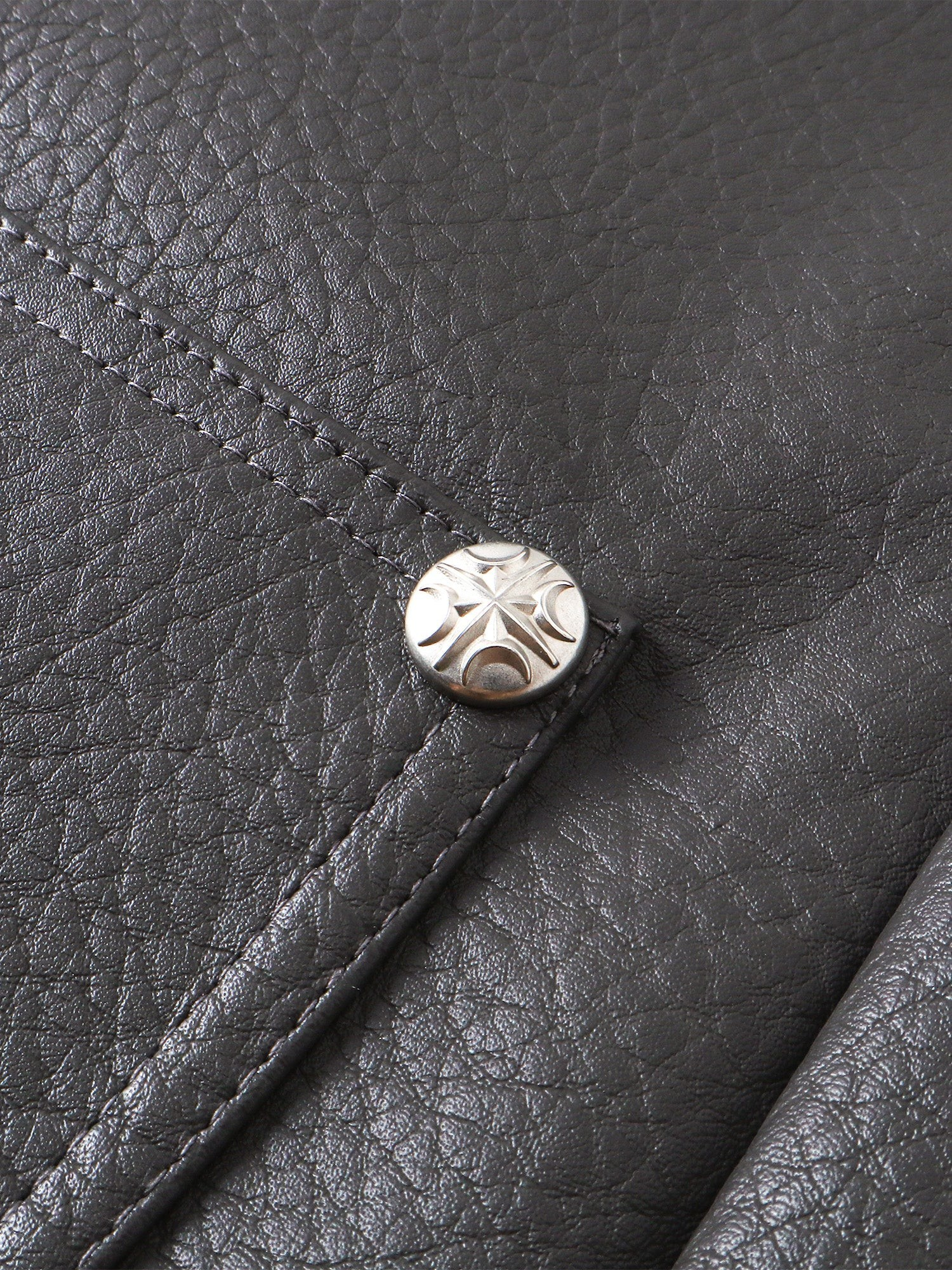 Close-up of the metal button on TBHNP faux-leather shorts — men's streetwear detail