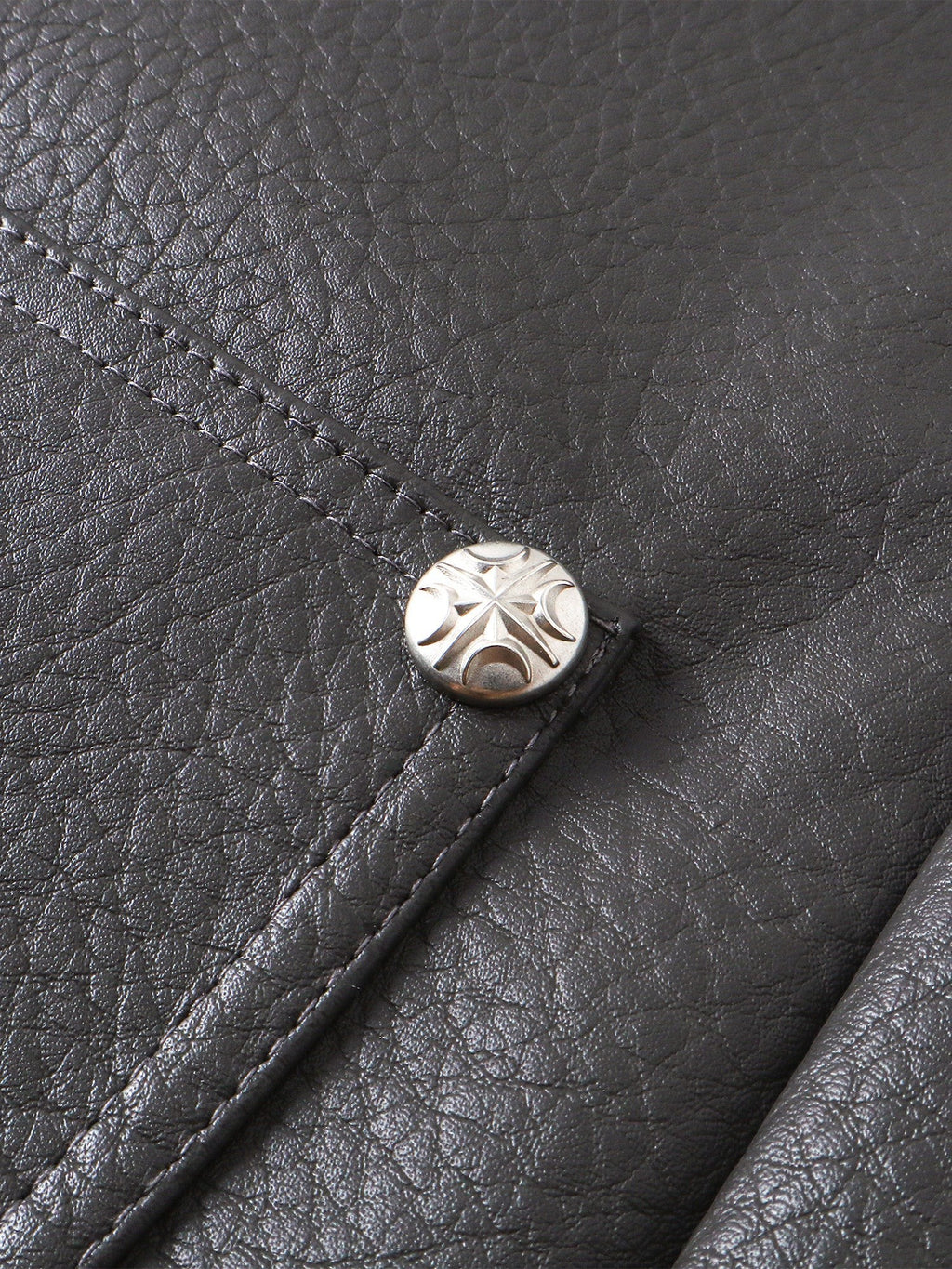 Close-up of the metal button on TBHNP faux-leather shorts — men's streetwear detail