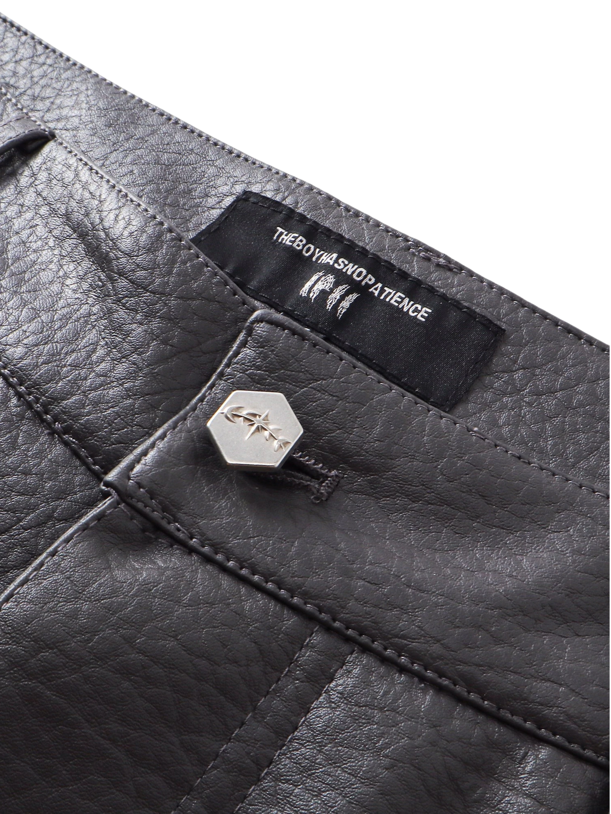 Close-up of the button fly on TBHNP black faux-leather shorts — men's streetwear detail