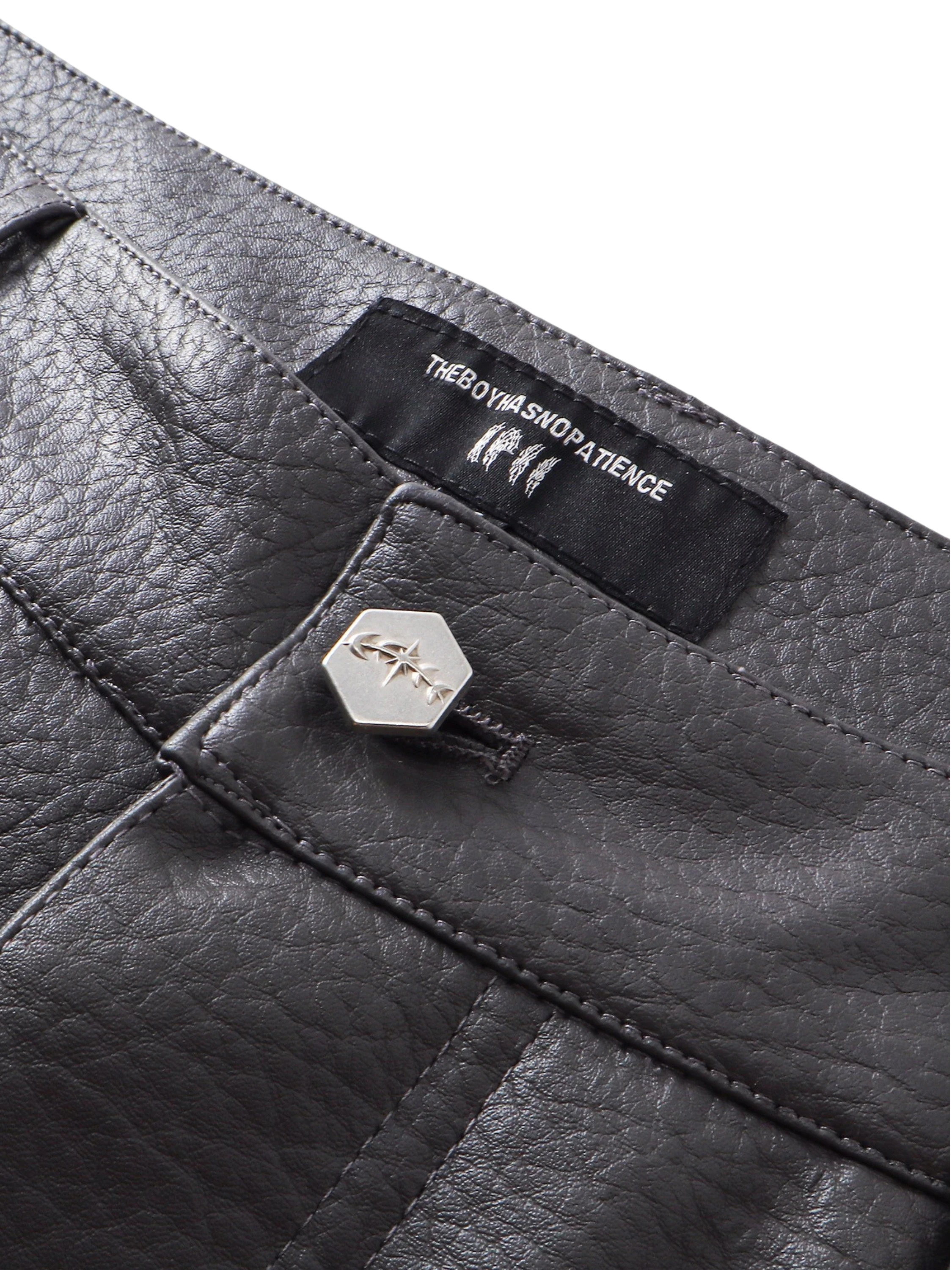 Close-up of the button fly on TBHNP black faux-leather shorts — men's streetwear detail