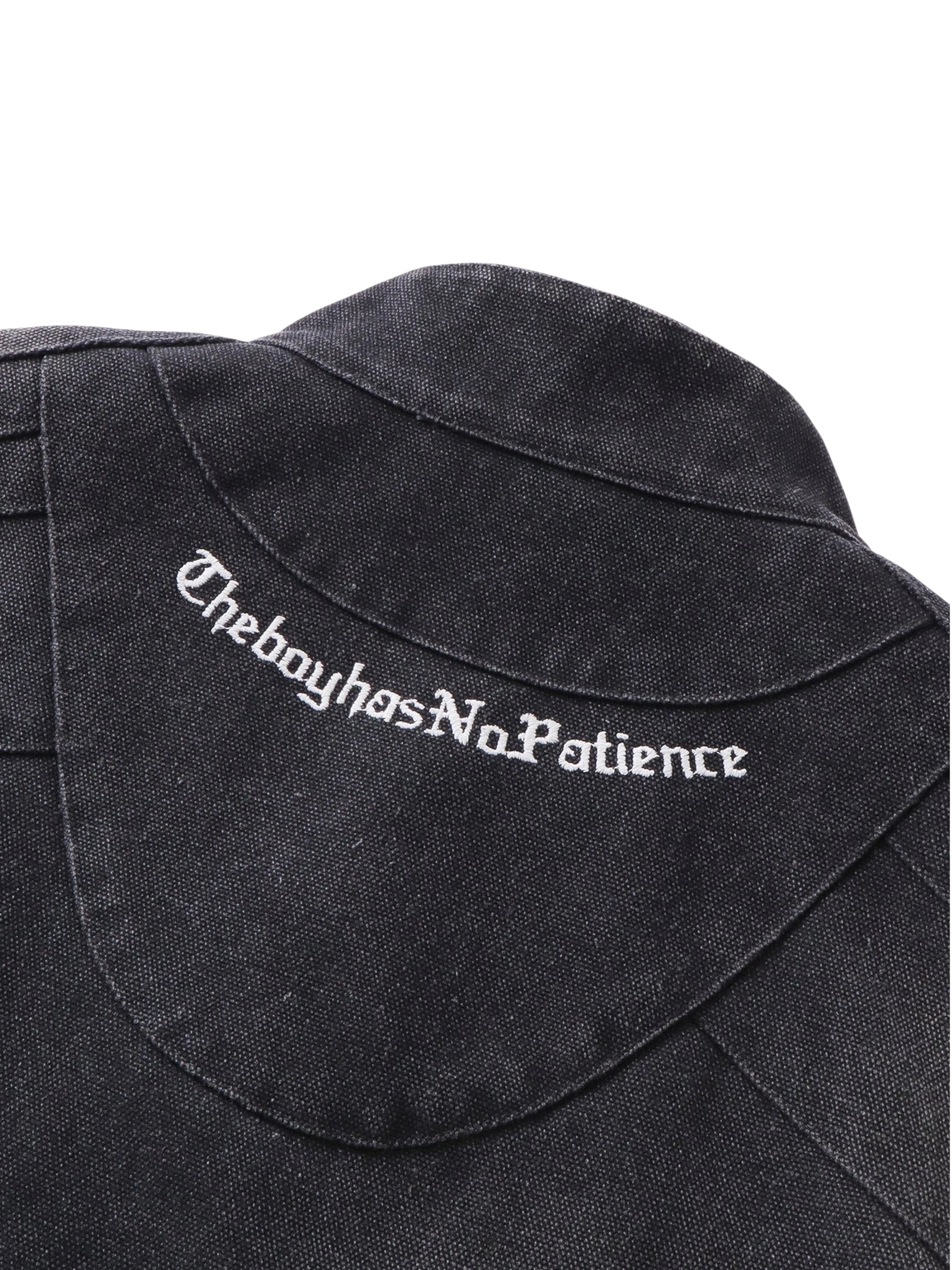 Close-up of TheBoyHasNoPatience embroidered branding on the canvas moto jacket — men's streetwear detail