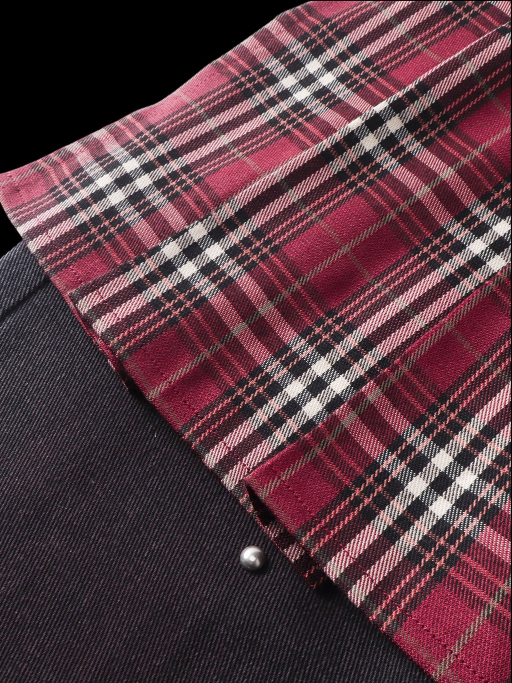Close-up of the burgundy plaid mini-skirt fabric and raw edge on TBHNP trousers — men's streetwear detail