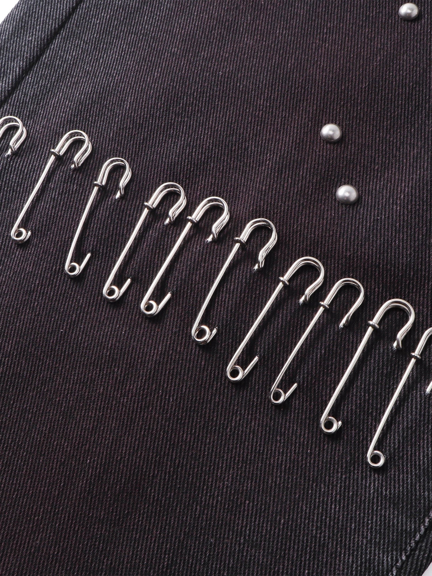Close-up of the safety-pin detailing on TBHNP spray-washed trousers — men's streetwear detail