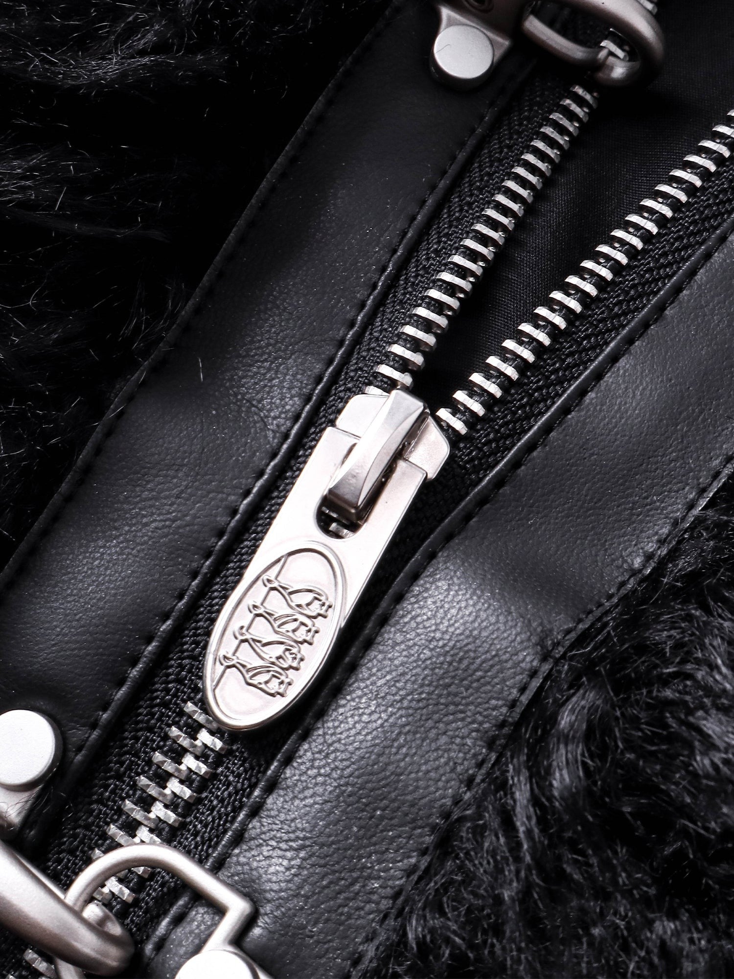 Close-up of the engraved zip pull on TBHNP Eclipse faux-fur bomber — men's streetwear detail
