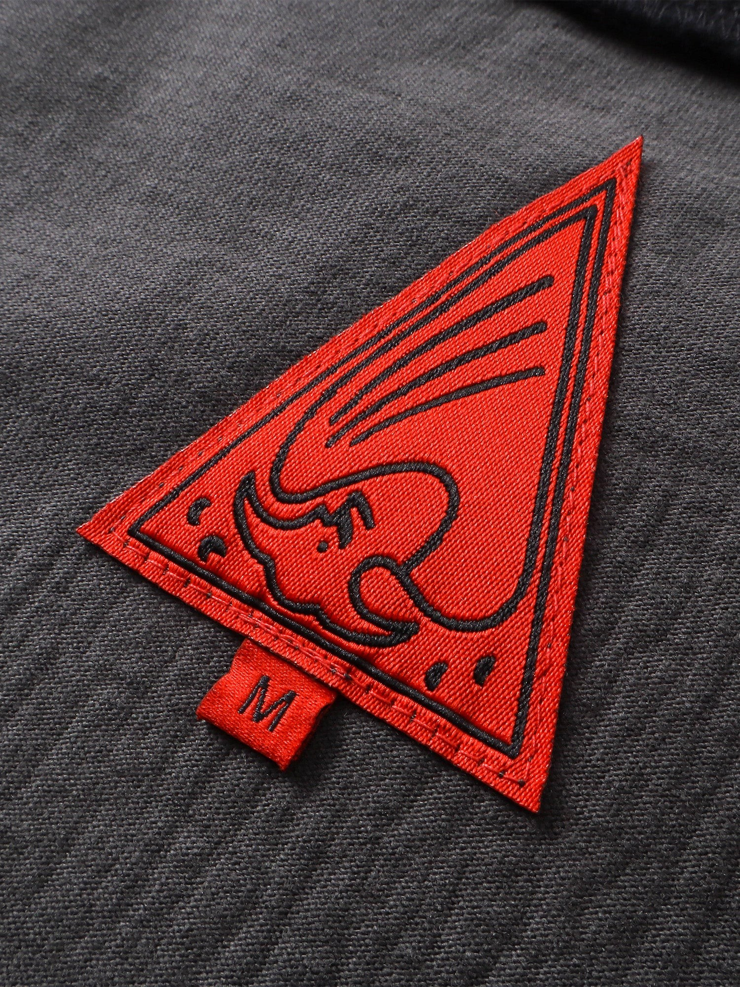 Close-up of the red triangle logo patch on TBHNP black knight tee — men's streetwear detail