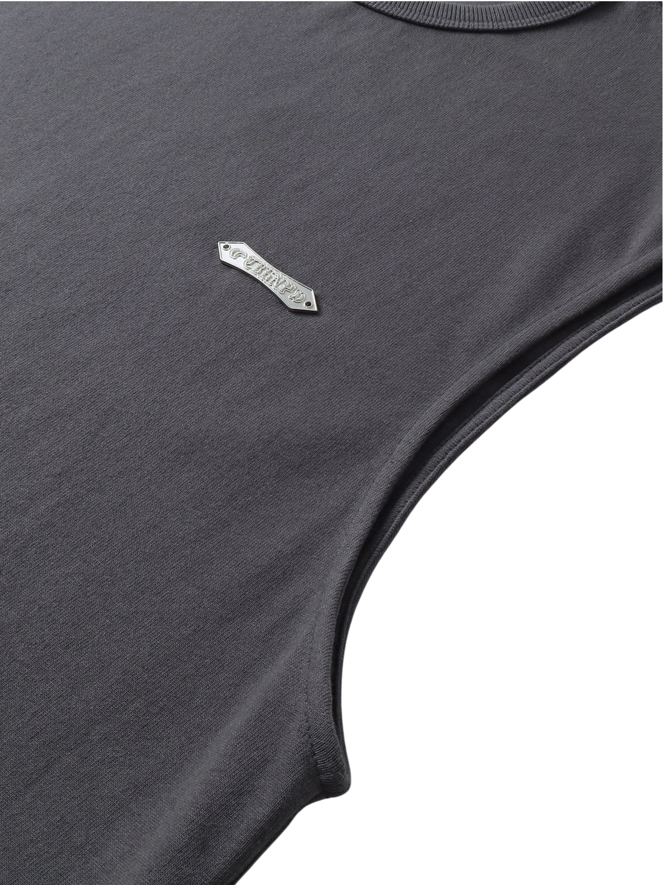 Close-up of the metal logo label on TBHNP dark grey Shadowbat vest — men's streetwear detail