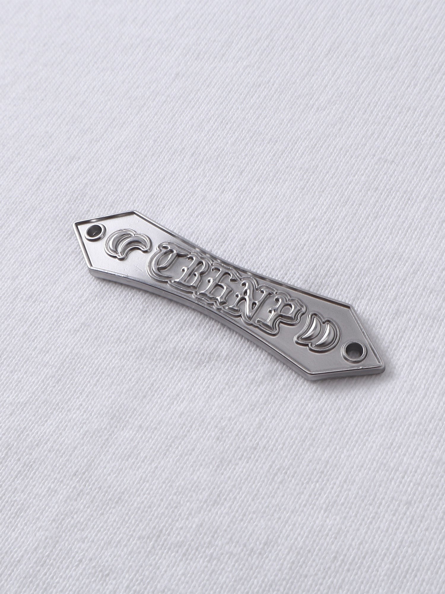 Close-up of the metal label on TBHNP Emblem & Shadowbat tee — men's streetwear detail