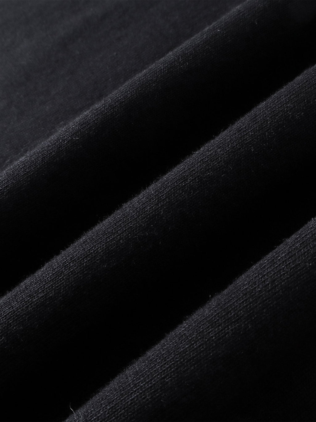 Close-up of the cotton texture on TBHNP black Emblem & Shadowbat tee — men's streetwear detail