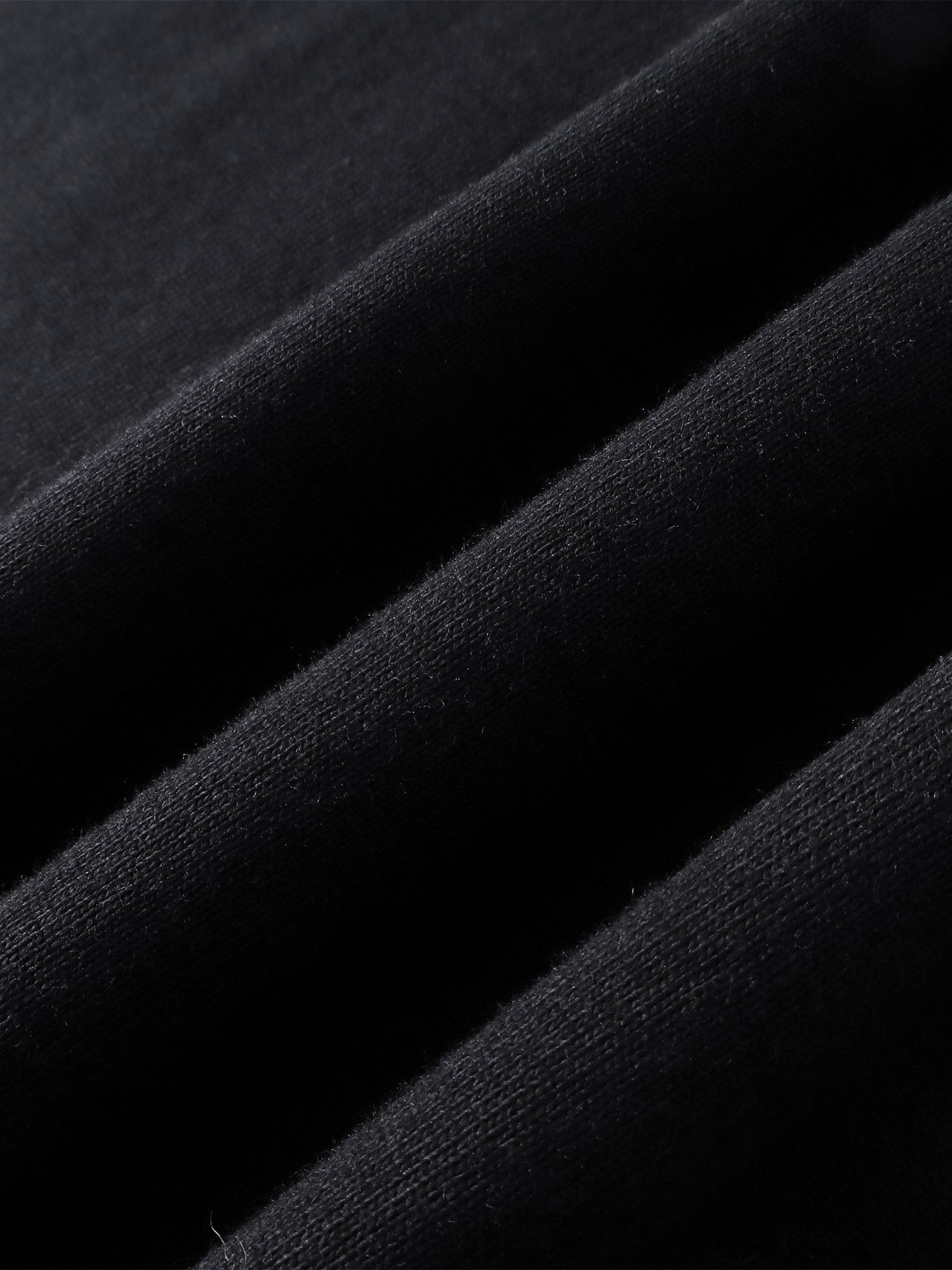 Close-up of the cotton texture on TBHNP black Emblem & Shadowbat tee — men's streetwear detail