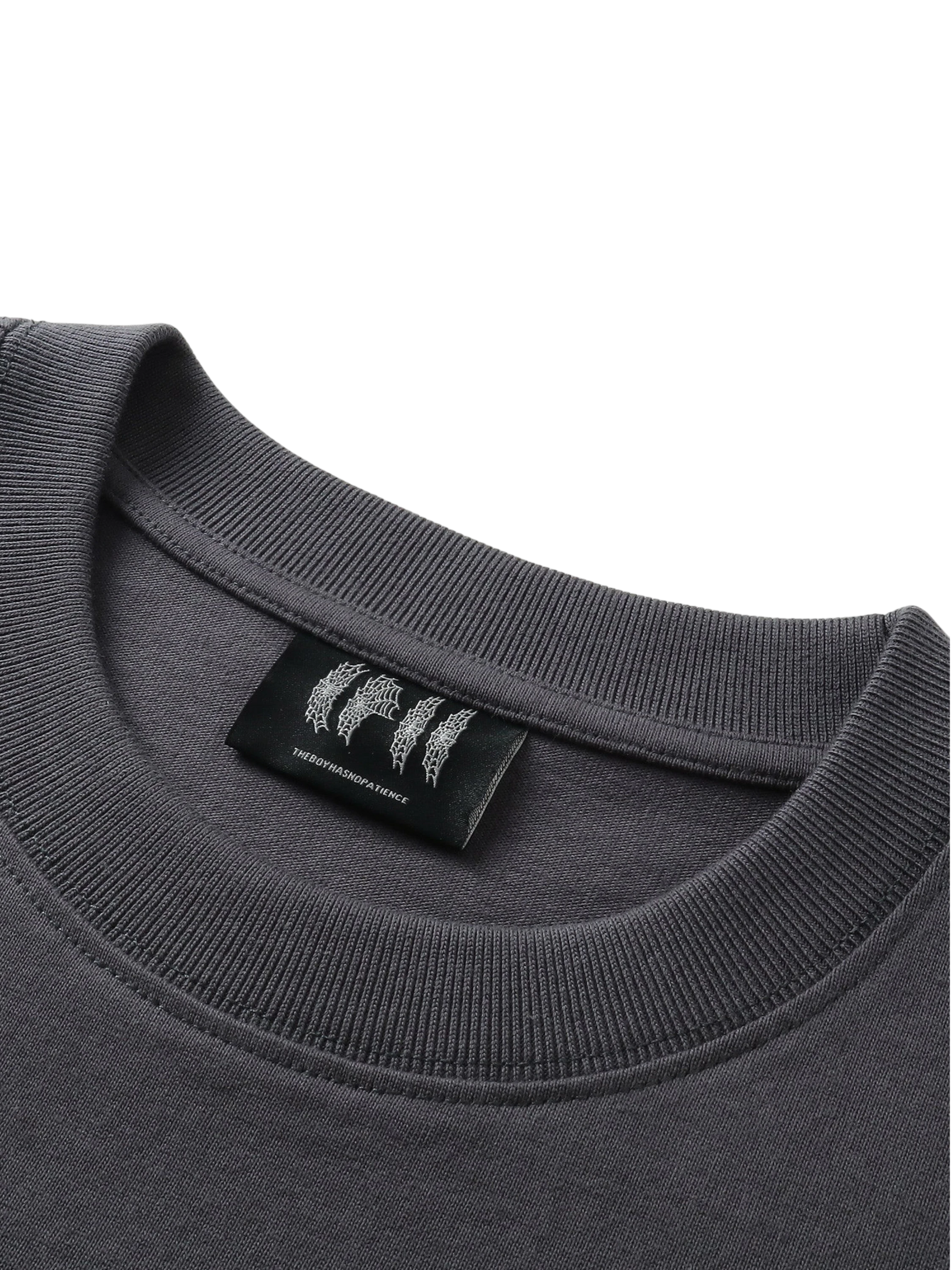 Close-up of the woven label on TBHNP Emblem & Shadowbat tee — men's streetwear detail