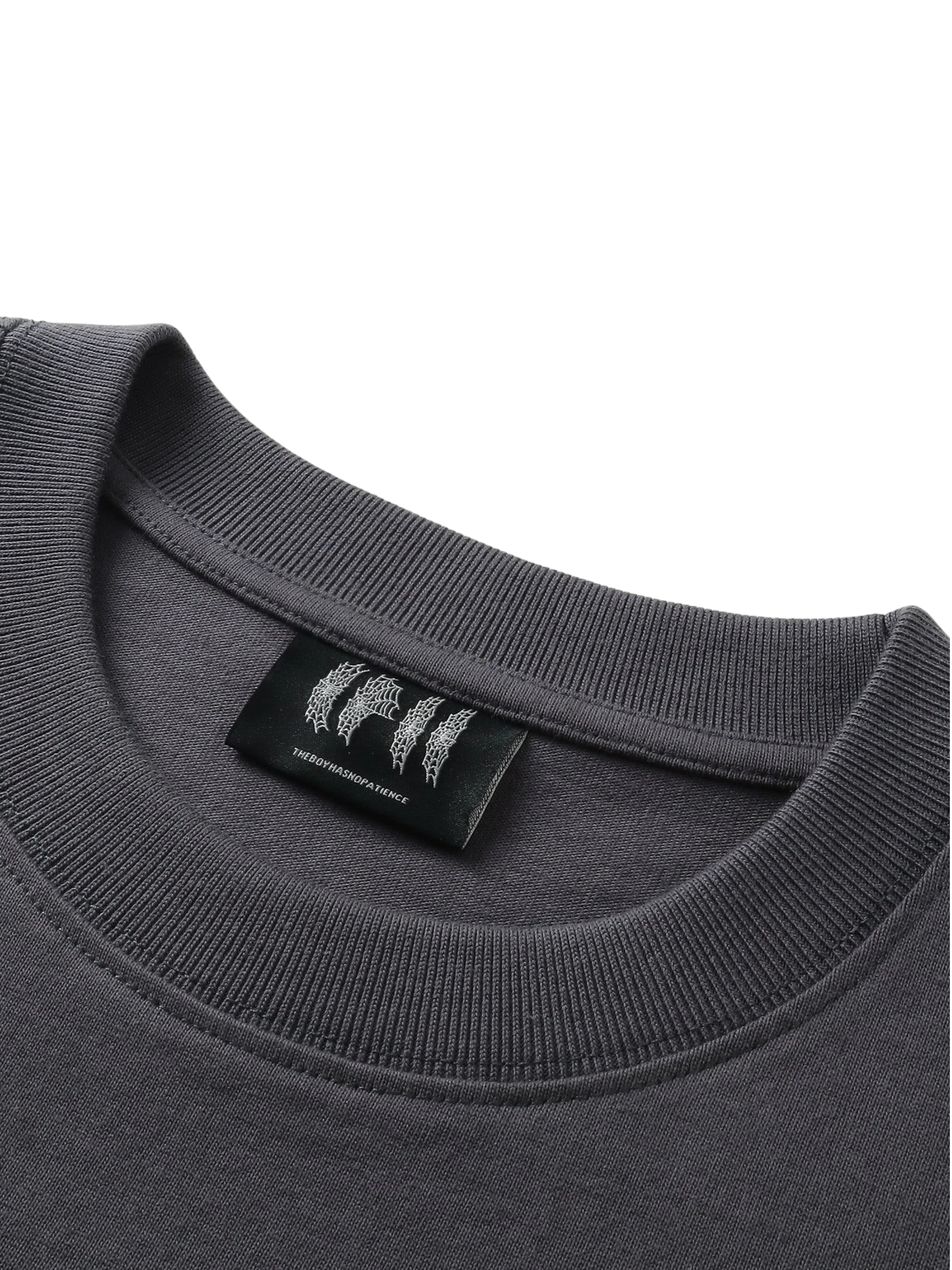 Close-up of the woven label on TBHNP Emblem & Shadowbat tee — men's streetwear detail